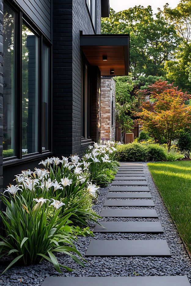 White lilies and dark stone path beside modern black house