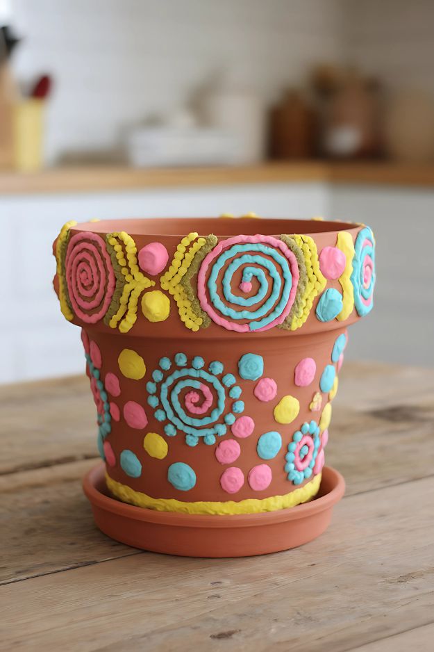 A pot with colorful puffy paint designs like swirls, dots, and hearts.