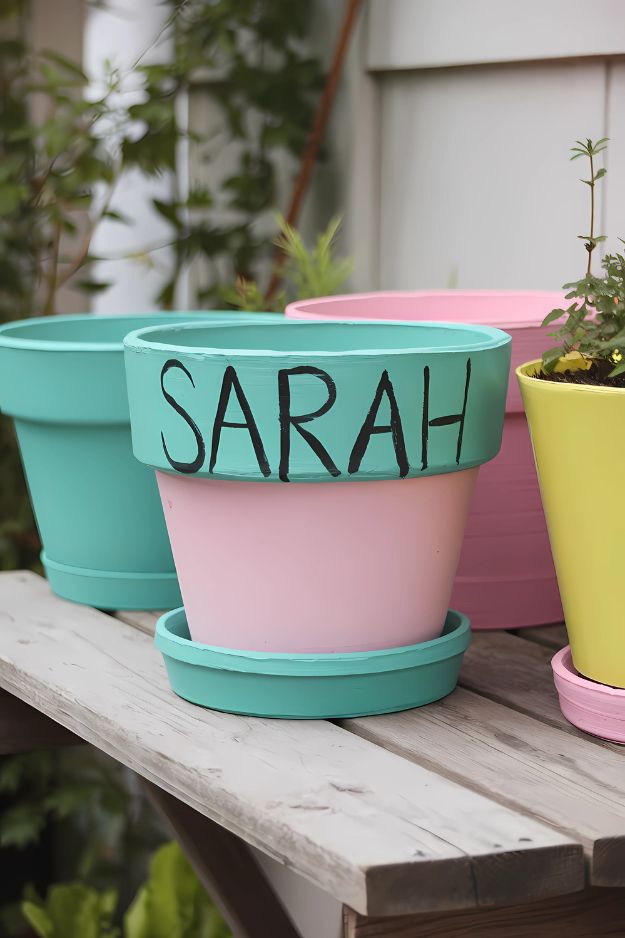 A pastel-painted pot with a child’s name written across the top in bold black letters.