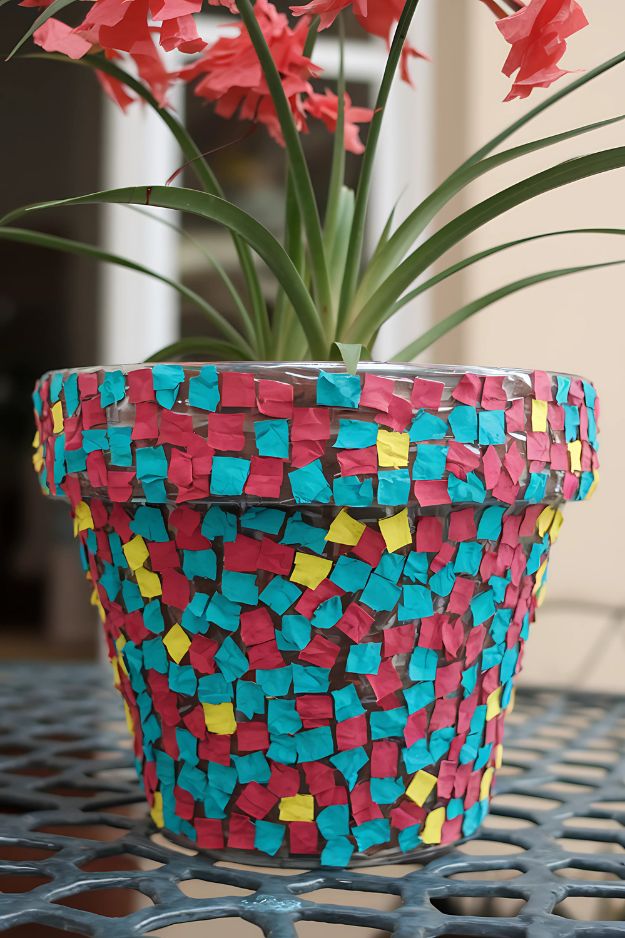 A terracotta flower pot covered in small square pieces of colorful tissue paper.