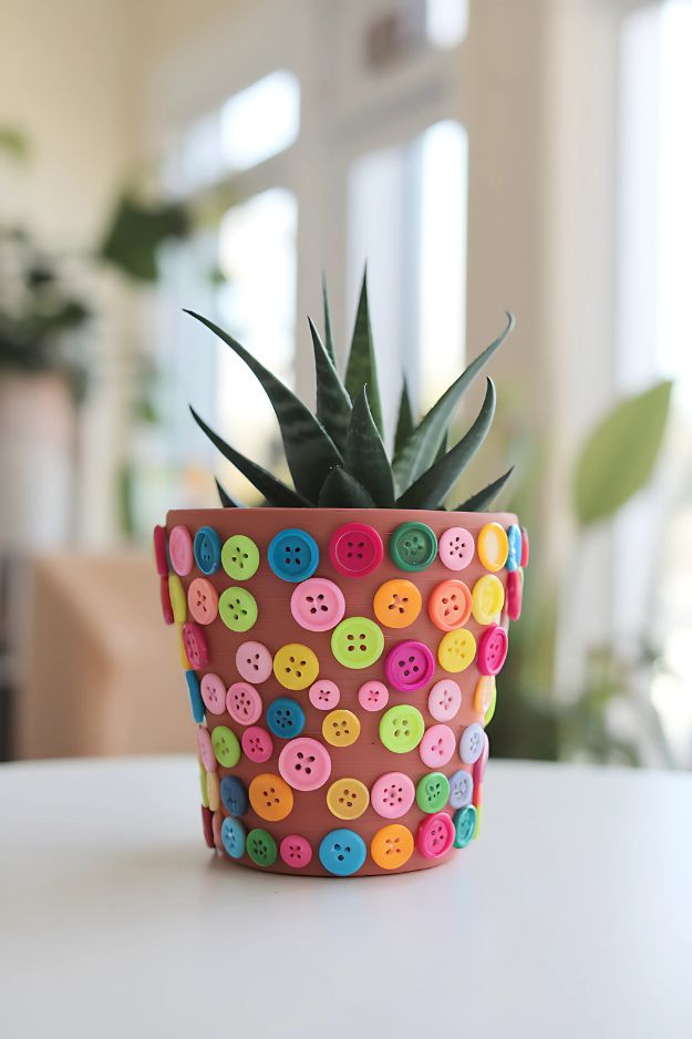 A terracotta pot decorated with colorful craft buttons glued all over the surface