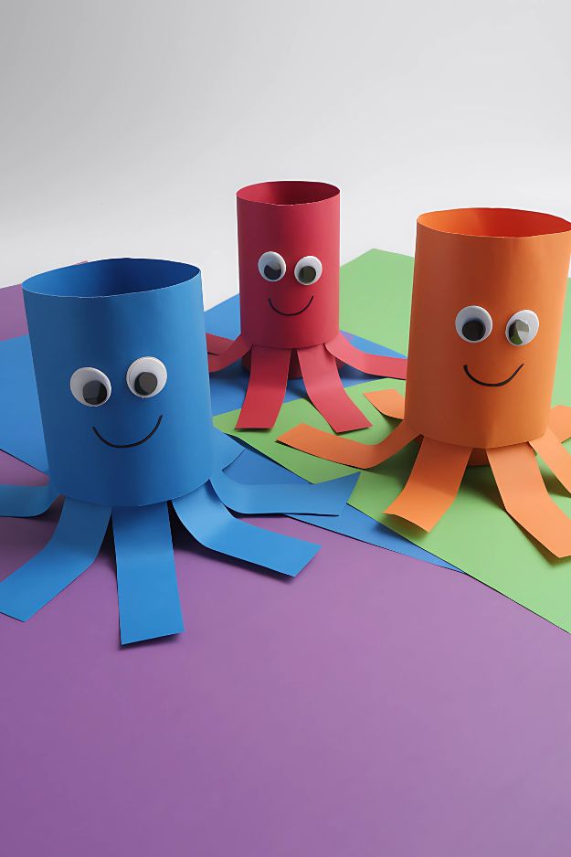 Blue, red, and orange paper octopus crafts with googly eyes and smiling faces.