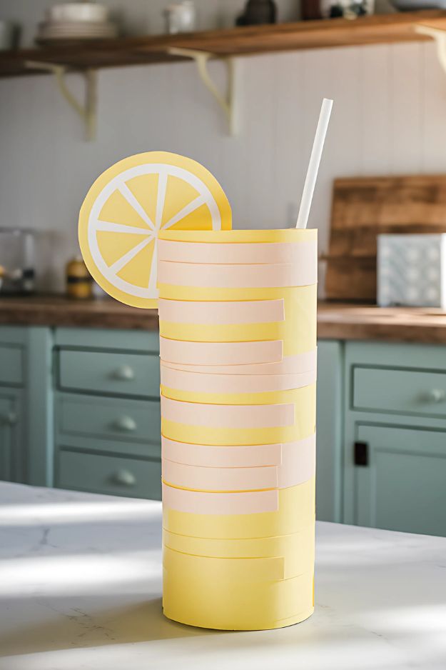 Tall paper lemonade cup craft with a straw and lemon slice in a kitchen setting.