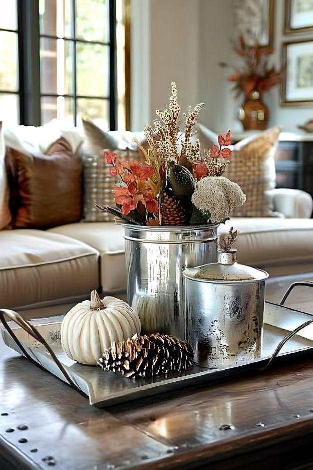 Silver containers with fall florals, pinecones, and white pumpkin on a large metal tray.