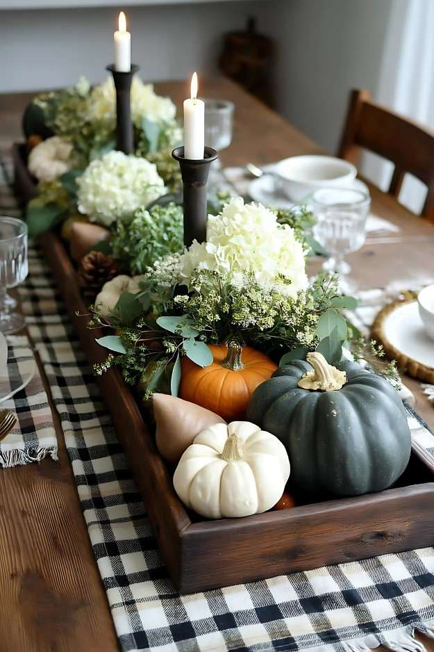 Fall centerpiece with white hydrangeas, pumpkins, and candles in a rustic wooden tray