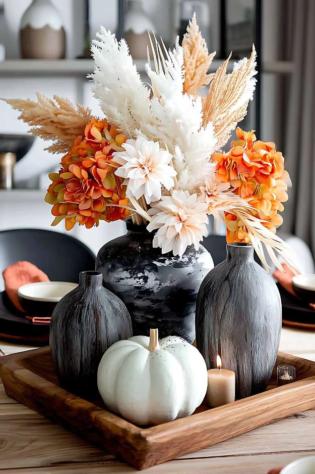 Bold fall centerpiece with black vases, orange florals, and a white pumpkin