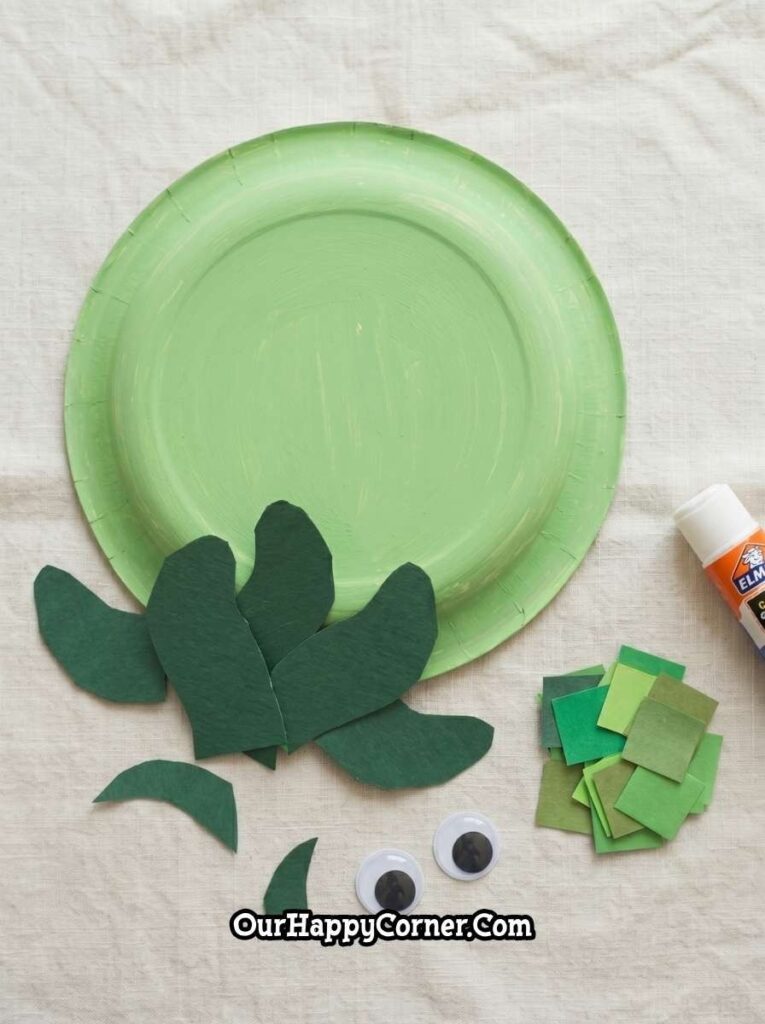 paper plate painted light green with cut paper pieces nearby