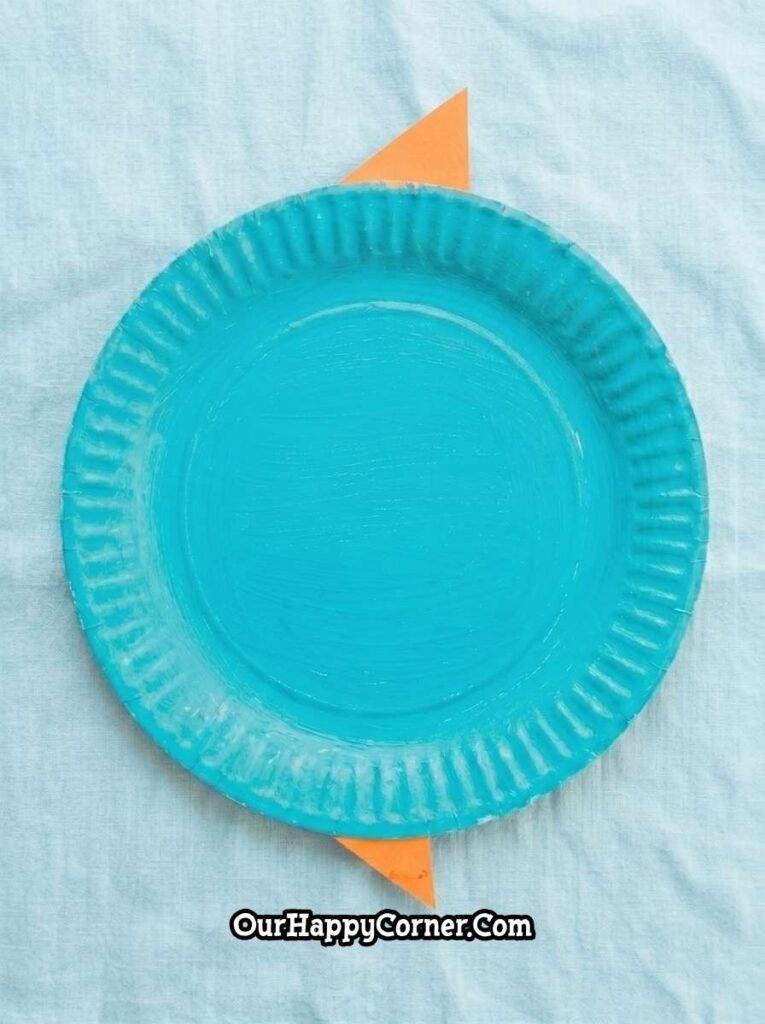 Blue painted plate with orange paper fins attached behind the top and bottom
