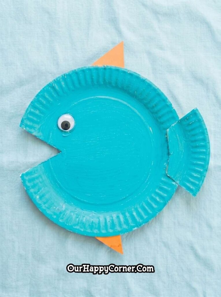 Cut-out mouth, googly eye, orange fins, and tail attached from a second paper plate
