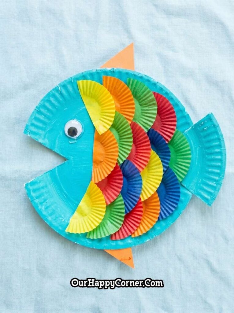 Finished paper plate fish craft with colorful layered cupcake liner scales.