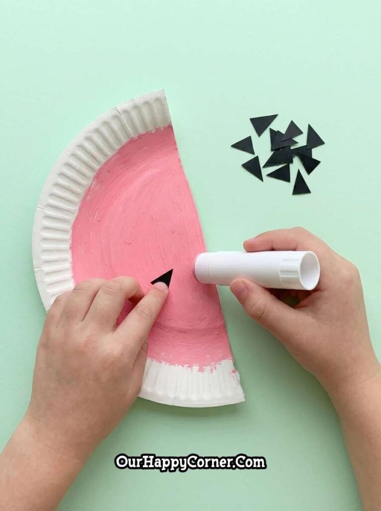 Cutting painted paper in half to form watermelon slices
