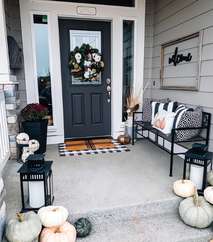 Front porch with black door, modern decor, and black and white fall-themed accessories.