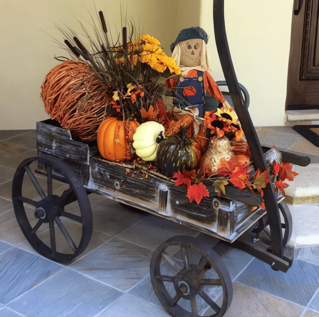 An antique wagon filled with autumn decorations including pumpkins, flowers, and a scarecrow