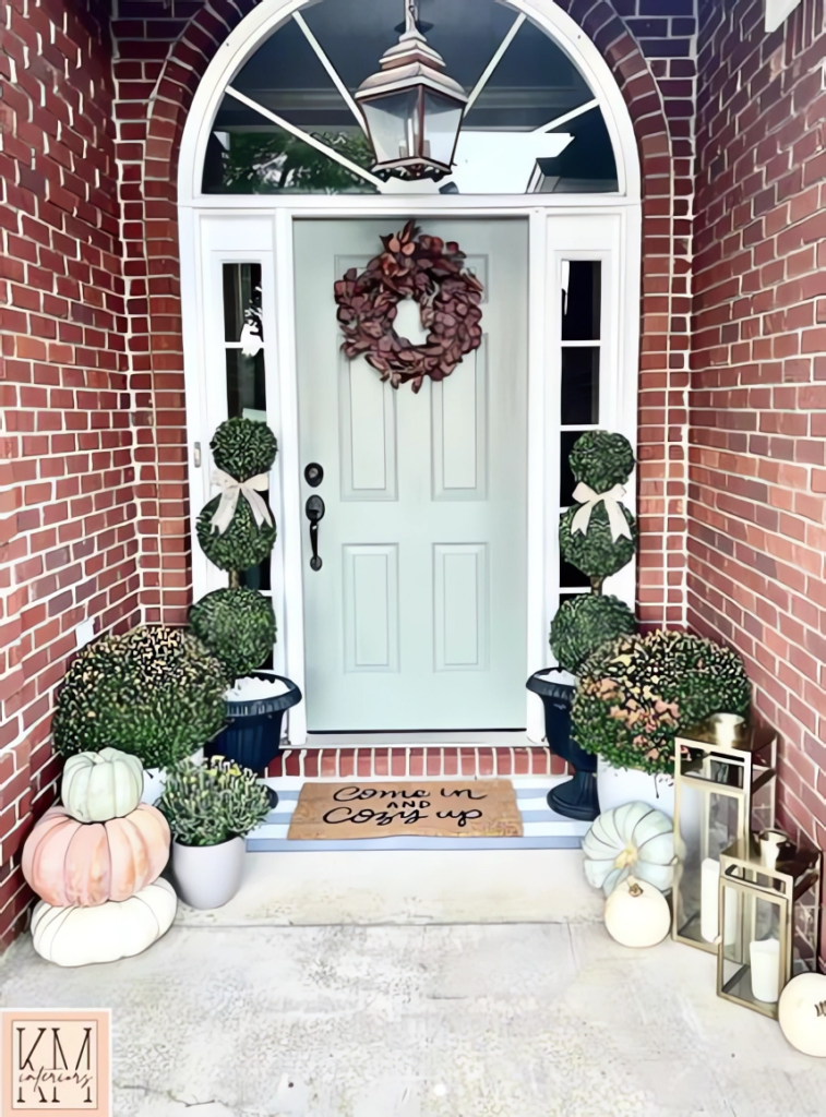 A refined front entrance decorated for fall with topiaries, pumpkins, and a wreath.