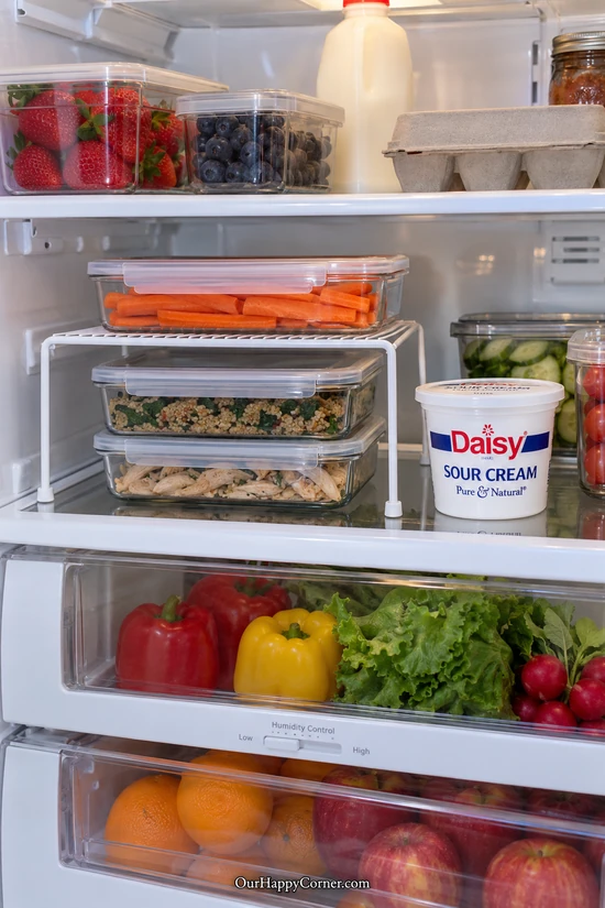 White refrigerator shelf riser above shallow covered leftovers