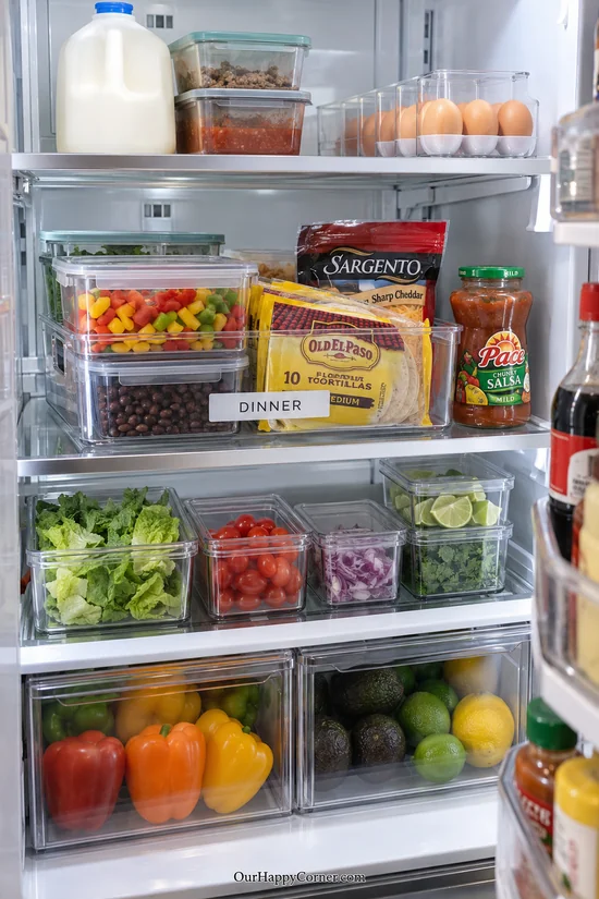 Clear dinner bin with taco ingredients and covered prepared vegetables
